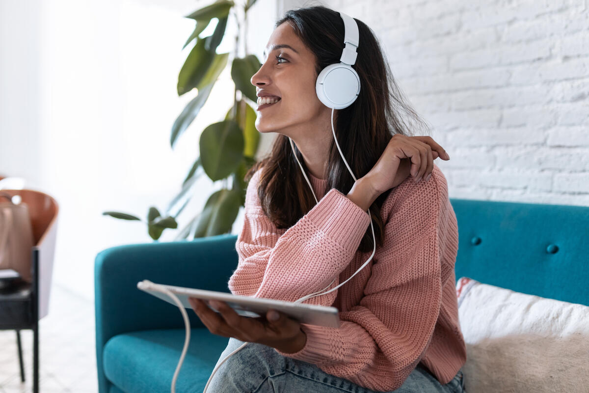 Woman on a couch listening to the Degrees podcast with headphones