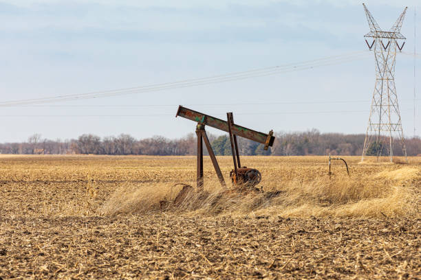 Old, orphaned oil well pump in farm field