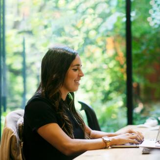 Young woman smiling and typing on a computer