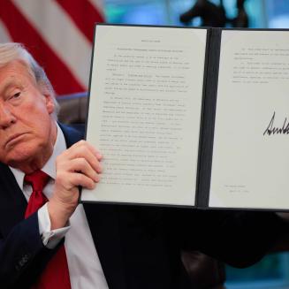 Donald Trump holding up a signed executive order