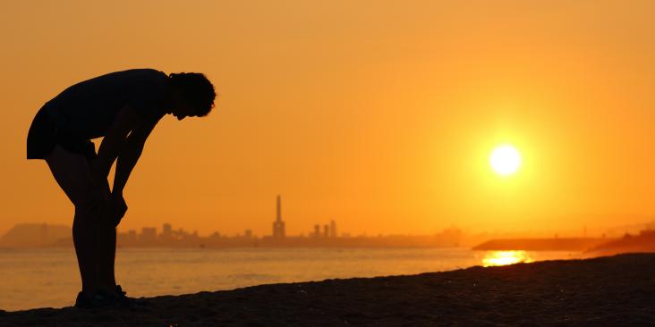 Horizon, person on beach bending over in heat