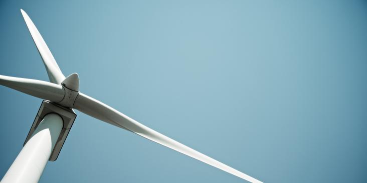 A windmill viewed from below, against a blue sky.