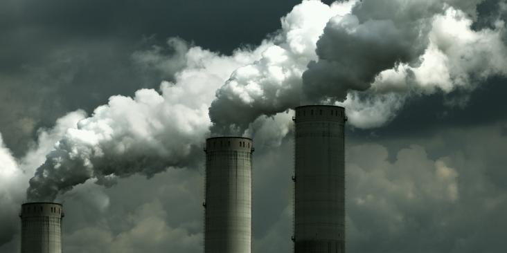Smokestacks releasing emissions on a cloudy day.