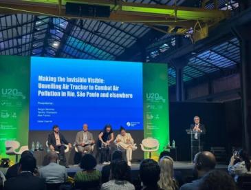 An audience watches a presentation titled, "Making the invisible visible: Unveiling Air Tracker to combat air pollution in Rio, Sao Paulo and elsewhere."